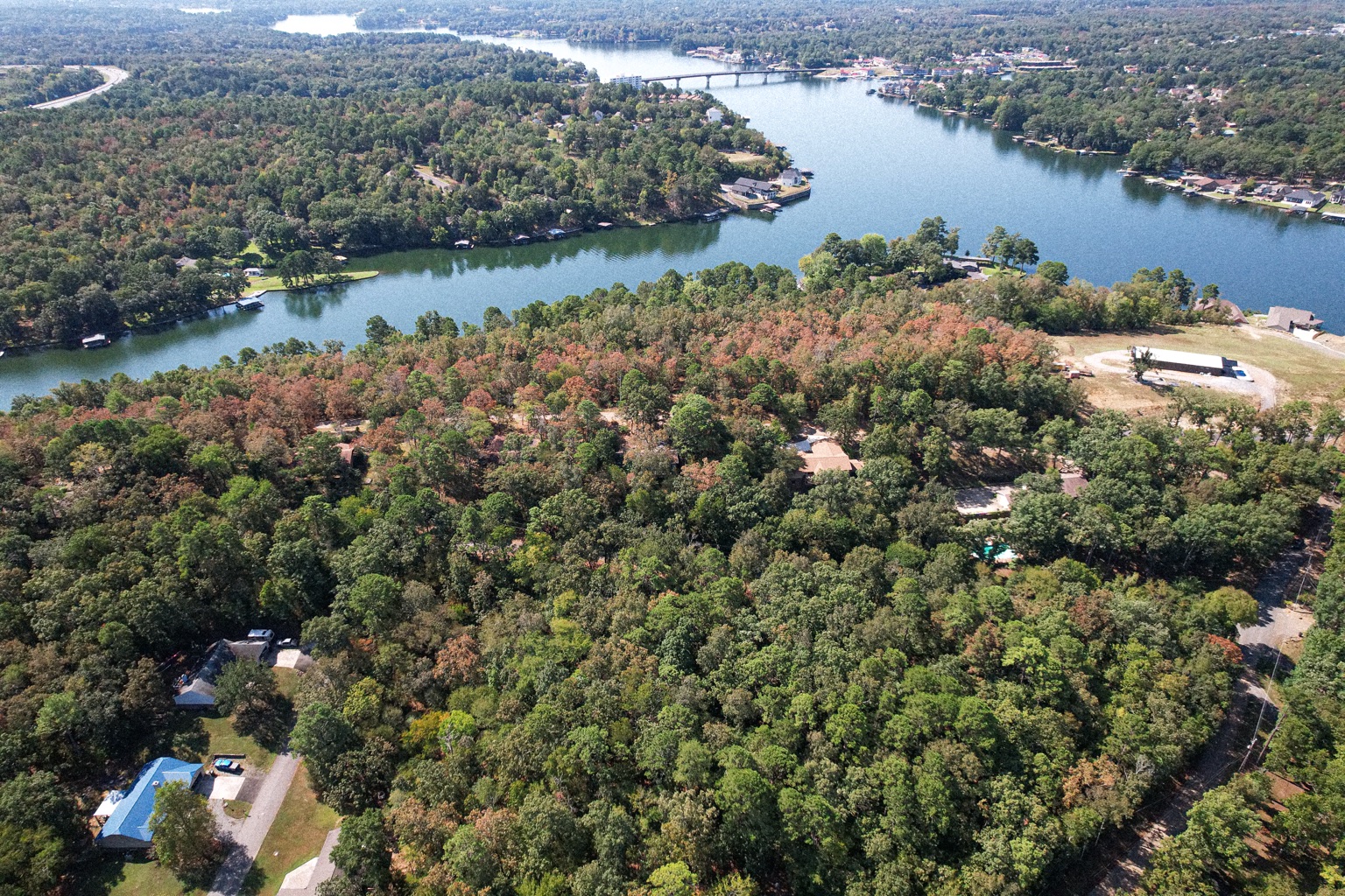 Wide aerial photograph showing a wooded property and the surrounding lake community