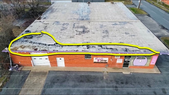 Annotated drone roof inspection highlighting visible deterioration and debris buildup along the front edge of a commercial flat roof