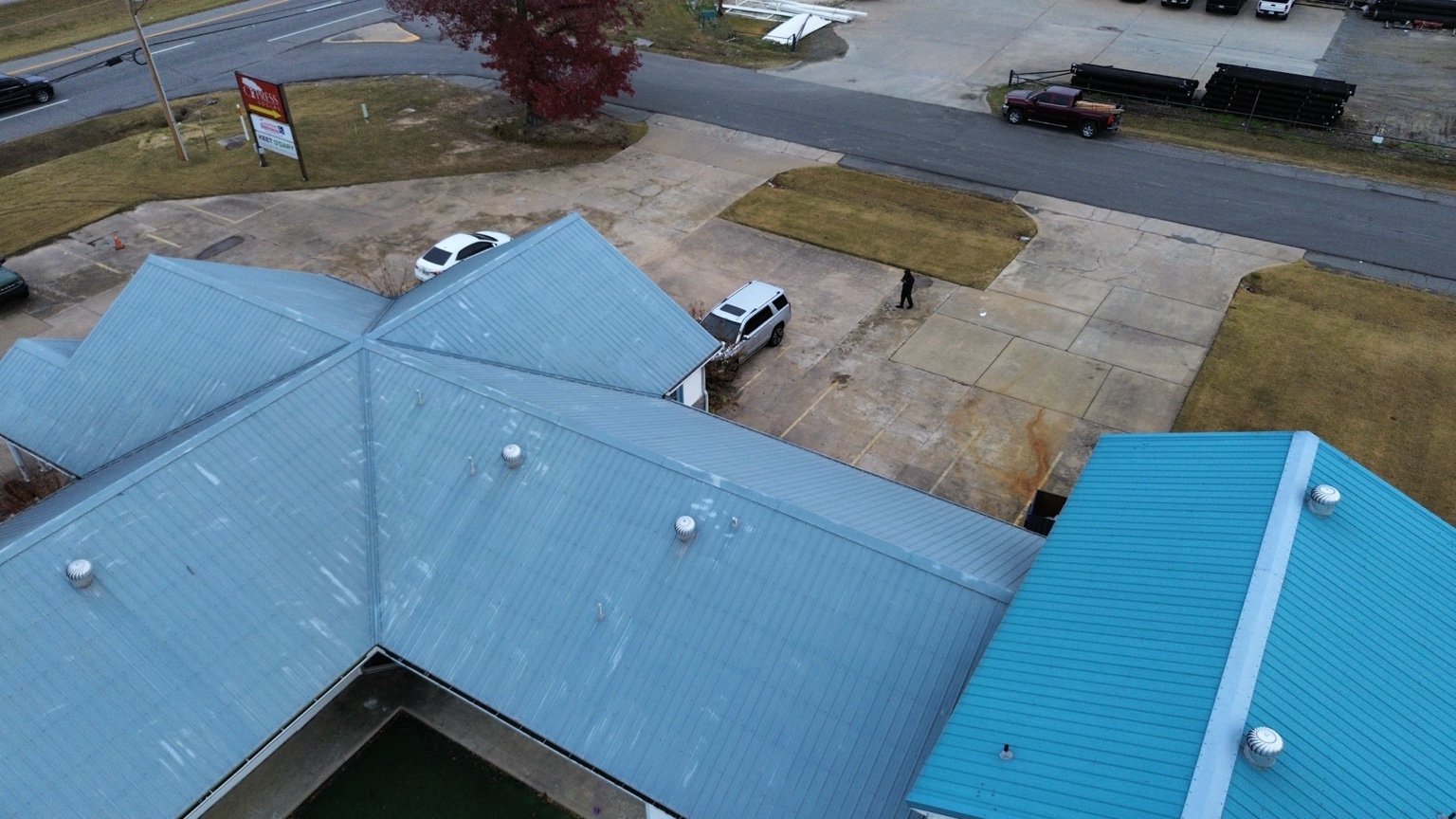 Close aerial inspection view showing metal roof panels, ridges, and vents
